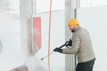 Man washing electric car at self-service car wash