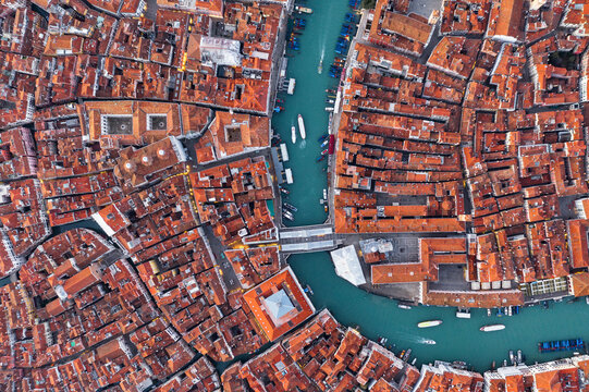 Aerial view of terracotta rooftops cascading around winding turquoise canals, a maze of history and beauty, Venice, Veneto, Italy.