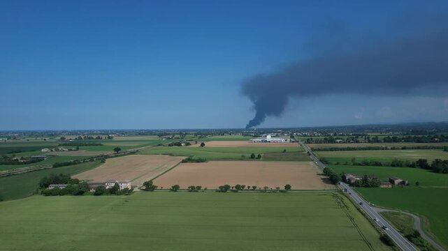 Industrial plant pollution spreads toxic black smoke over cultivated farmlands