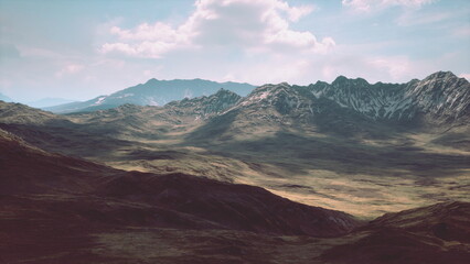 Obraz premium A breathtaking mountain landscape unfolds under soft afternoon light, revealing rugged peaks and a sprawling green valley. Shadows dance across the terrain, enhancing the beauty of nature.