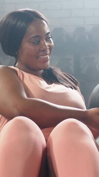 Vertical video: Reaching woman in pink set rotating and passing medicine ball 3 in gym for core