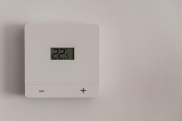 Minimal white digital thermostat on wall displaying room temperature