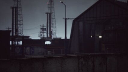 Obraz premium Under a dim sky, an industrial setting comes alive. Towering structures and power poles create a stark silhouette against the fading light, evoking a sense of mystery and intrigue.