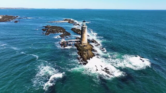Aerial view of the Ram Island Ledge Light surrounded by the turbulent sea, with the white waves contrasting against the darker rocks, Portland, Maine, United States.