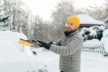 Man clearing snow from car windshield in winter weather