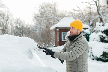 Man clearing snow from car windshield in winter