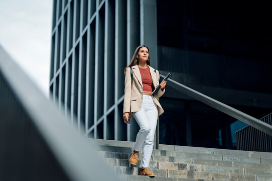 Elegant young businesswoman going down the street stairs.