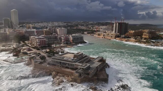 Aerial view of the buildings and rough seas, the waves crashing against the rocks, St. Julian's, Malta.