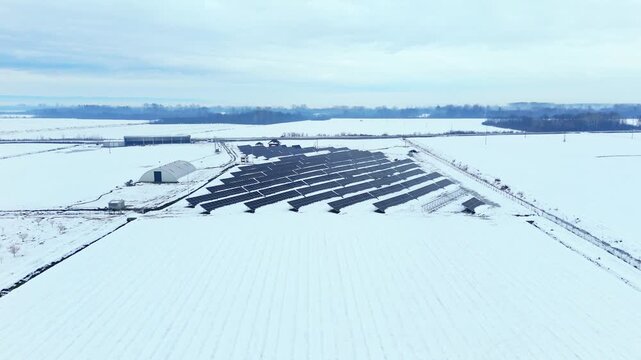 Aerial view of rows of dark solar panels contrasting with the white snow-covered ground, creating a striking pattern, Sremska Mitrovica, Vojvodina, Serbia.