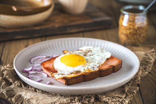 One slice of Leberkaese with fried egg on a wooden table