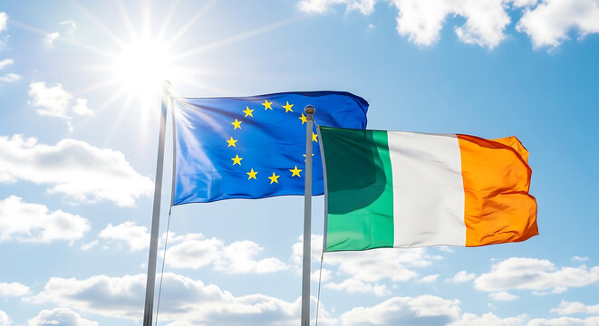 The European Union and Irish flags waving in the wind on a sunny day with blue sky