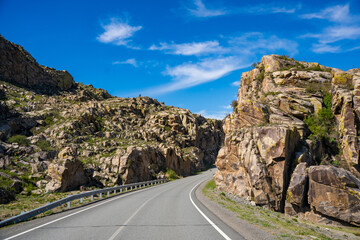 Asphalt road passing through stone cliffs at Stone Gates Chuysky Trakt Altai Russia. Iconic mountain pass framed by towering rocky formations.