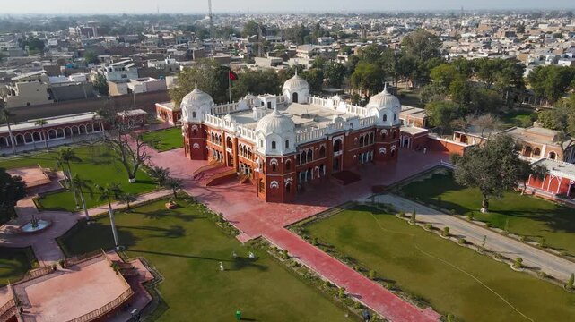 Aerial view of Barbar mahal bahawalpur, a red and white building surrounded by green grass, palm trees, and pathways, Bahawalpur, Punjab, Pakistan.