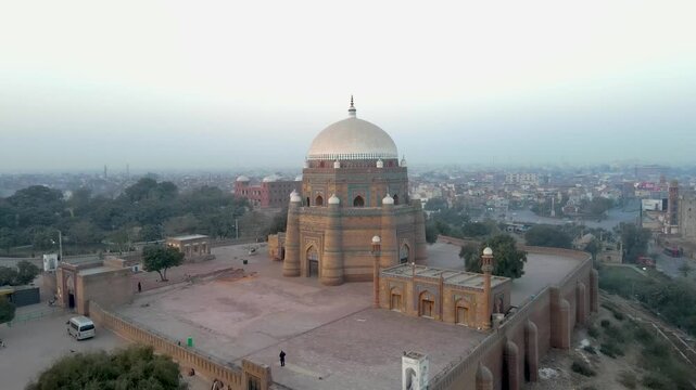Aerial view of the Tomb of Shah Rukn-e-Alam showcasing intricate brickwork and a gleaming white dome against the hazy cityscape, Multan, Punjab, Pakistan.