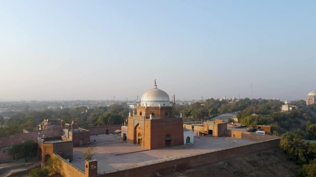 Aerial view of the Shrine of Bahauddin Zakariya, a complex of brick structures with white domes, standing out against the cityscape, Multan, Punjab, Pakistan.