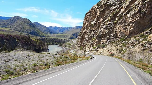 Road stretching along the Chuya River on Chuysky Trakt in Altai Russia. Scenic mountain route through wild Siberian landscape.