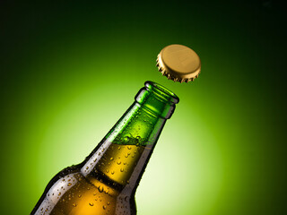 Cold beer bottle being opened with cap flying off