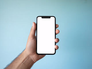 Hand holding smartphone with blank white screen against blue background