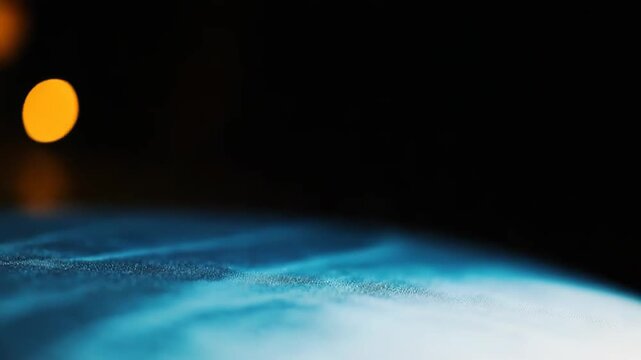 Distorted water drops creating an abstract textured surface on glass, with a blurred light source from the top right casting a soft glow, generating a background illustrating fluidity and change