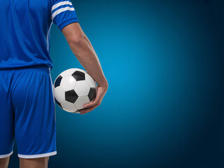 Soccer player holding ball against blue background