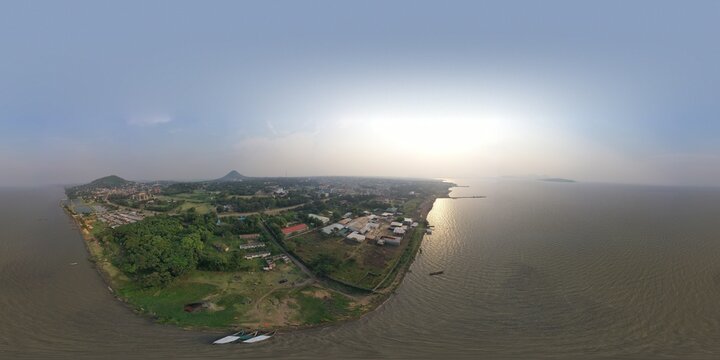 Aerial view of boats resting on the shores of Lake Victoria, the city sprawling with buildings and lush greenery under a hazy sky, Kisumu, Homa Bay, Kenya.