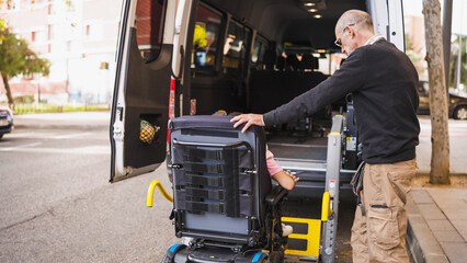 Man assisting person in wheelchair accessing mobility transport van with a specialized lift for inclusive urban travel © DMegias