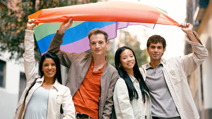 Group of happy young adults raising a rainbow flag, celebrating diversity and inclusion with smiles on a city street