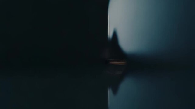 Abstract space featuring dark textured walls and a reflective floor leading towards an illuminated opening, symbolizing opportunity, a new beginning, or the unknown future