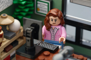 Fototapeta premium Tambov, Russian Federation - January 26, 2026 A Lego businesswoman minifigure sitting and working behind a computer in an office. Close up.