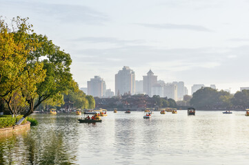 Fototapeta premium Winter landscape of leisure boats on the lake and city skyline in Moon Lake Park (Yuehu Park), Ningbo, China