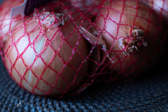 Raw onions in a red mesh bag.