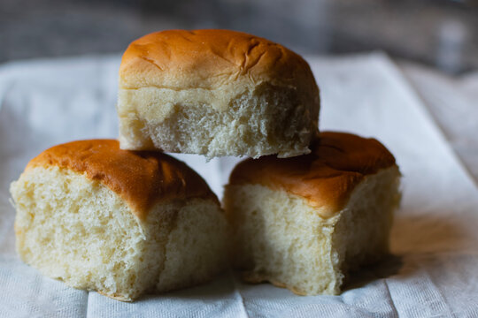 Three Hawaiian rolls piled on top of each other in a pyramid or triangular shape. 