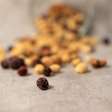 Isolated raising in front of spilled trail mix that is blurred in the background. 