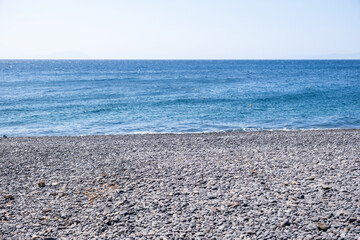 Obraz premium Mavra Volia beach, black pebble shore on Chios island, Greece, Calm Aegean Sea, soft waves splash on the coastline