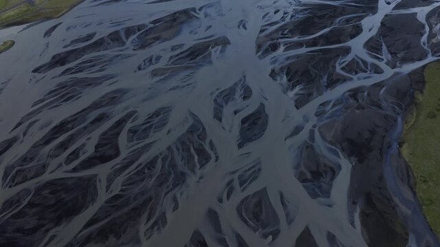 Aerial view of glacial rivers weave intricate patterns across the stark, dark landscape, creating a mesmerizing display of nature's artistry, Iceland.