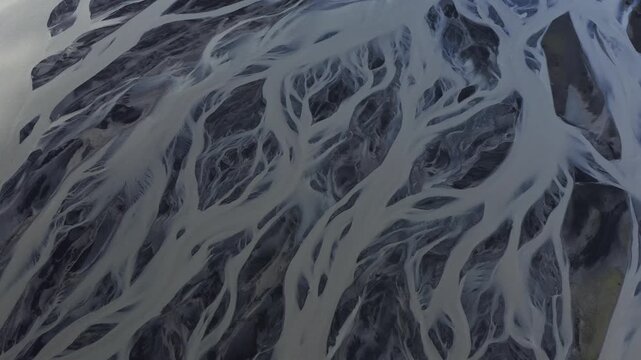Aerial view of braided glacial rivers creating stunning patterns with contrasting light and dark tones in the landscape, Svinafell, Iceland.
