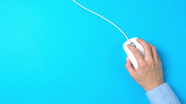 Hand holding computer mouse on blue background