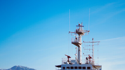 Fototapeta premium Ship navigation tower against clear blue sky with distant mountains visible