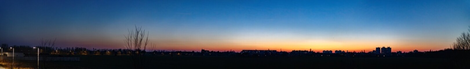 Naklejka premium Urban silhouette under vivid sunset sky panorama