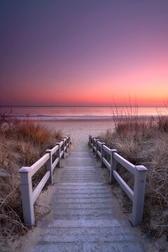 colorful sunrise over the sea with wooden footpath over dunes