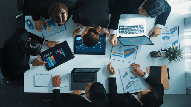 Top view of smart business people brainstorm marketing idea at meeting table while compare stock market investment data between laptop and tablet. Business team planning financial plan. Directorate. - Powered by Adobe