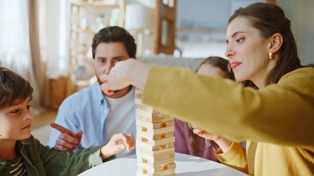 Cheerful family playing Jenga enjoying home leisure closeup. Boy holding balance