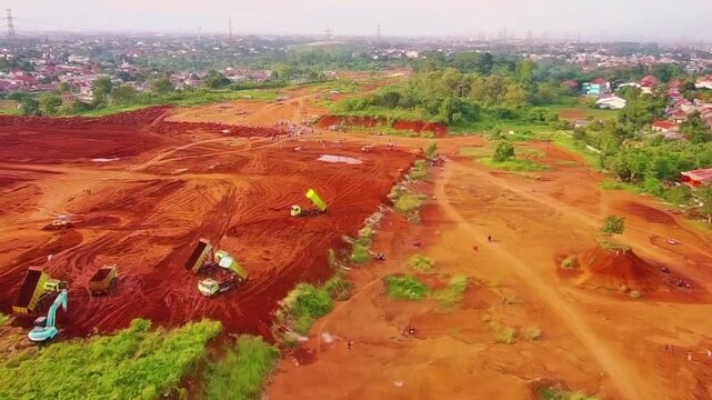 Aerial footage, large-scale land clearing, cutting down trees which are actually a source of life and home for animals, several heavy machines are seen working to collect soil