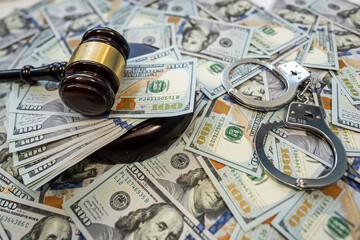 Judge gavel and handcuffs on dollar bills symbol of corruption and financial crime