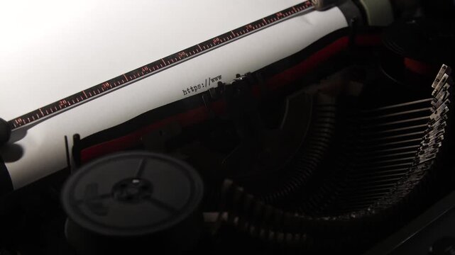 Vintage typewriter typing https,www. Onto a blank sheet of paper, symbolizing communication evolution and the contrast between old analog and modern digital technology