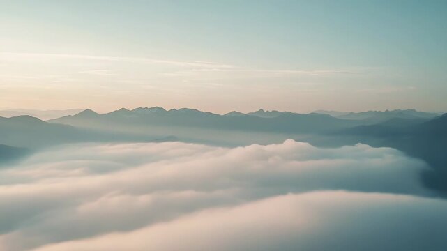Soft clouds completely covering a valley at sunrise, creating a peaceful and serene natural landscape with mountain ranges visible in the distance under a clear sky