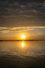 Obraz premium Golden Sunset over Industrial Harbor with Calm Water Reflections