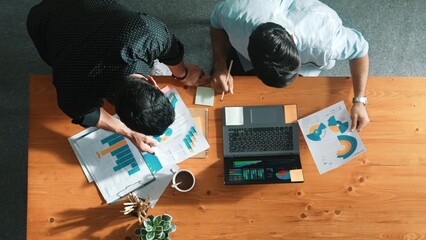 Obraz premium Skilled project manager walking at table while colleague brainstorm idea. Business team working together to plan marketing strategy while looking at data analysis or financial statistic. Convocation.