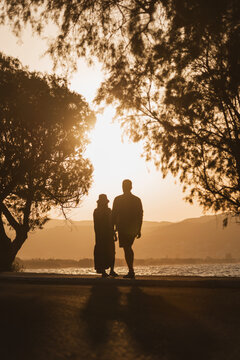 Romantic couple looking at the sea during golden sunset on summer vacation
