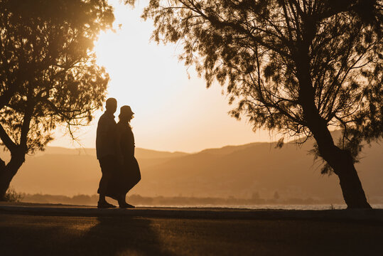 Romantic couple looking at the sea during golden sunset on summer vacation